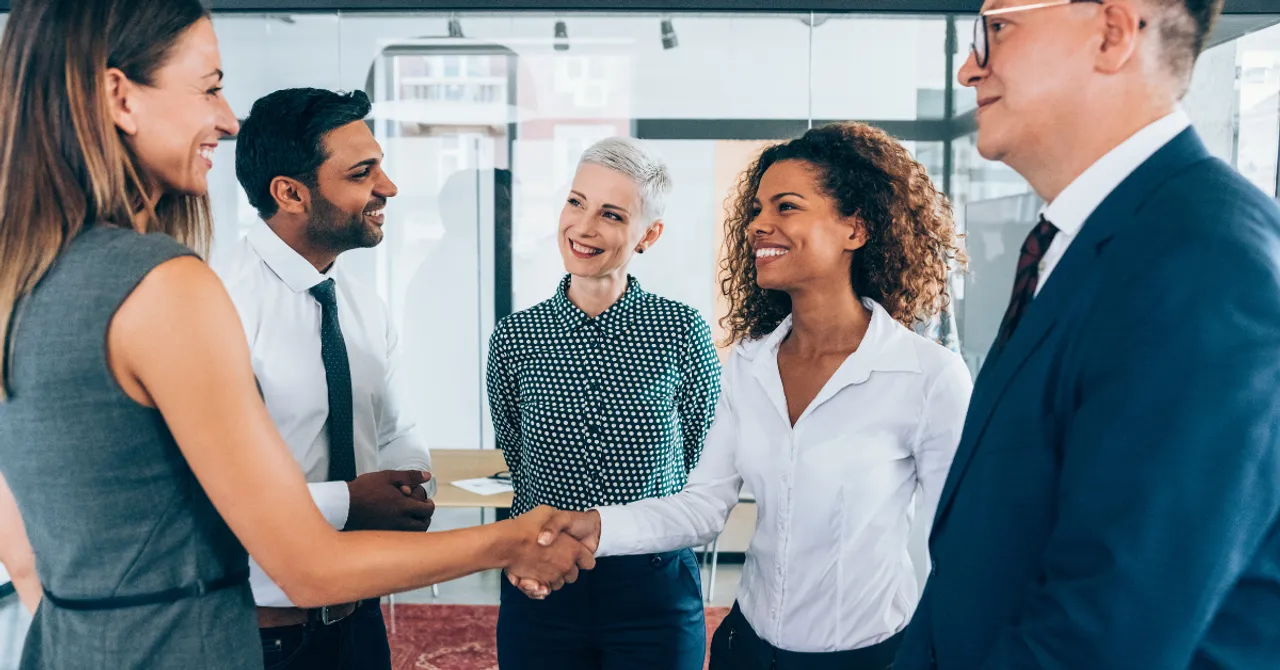 Diverse professionals shaking hands and smiling in a business meeting.