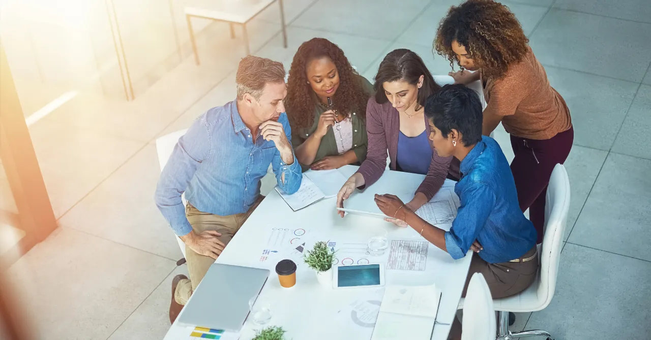 A diverse team collaborates around a table, analyzing data and planning strategy—highlighting the power of teamwork in driving eCommerce innovation and growth.