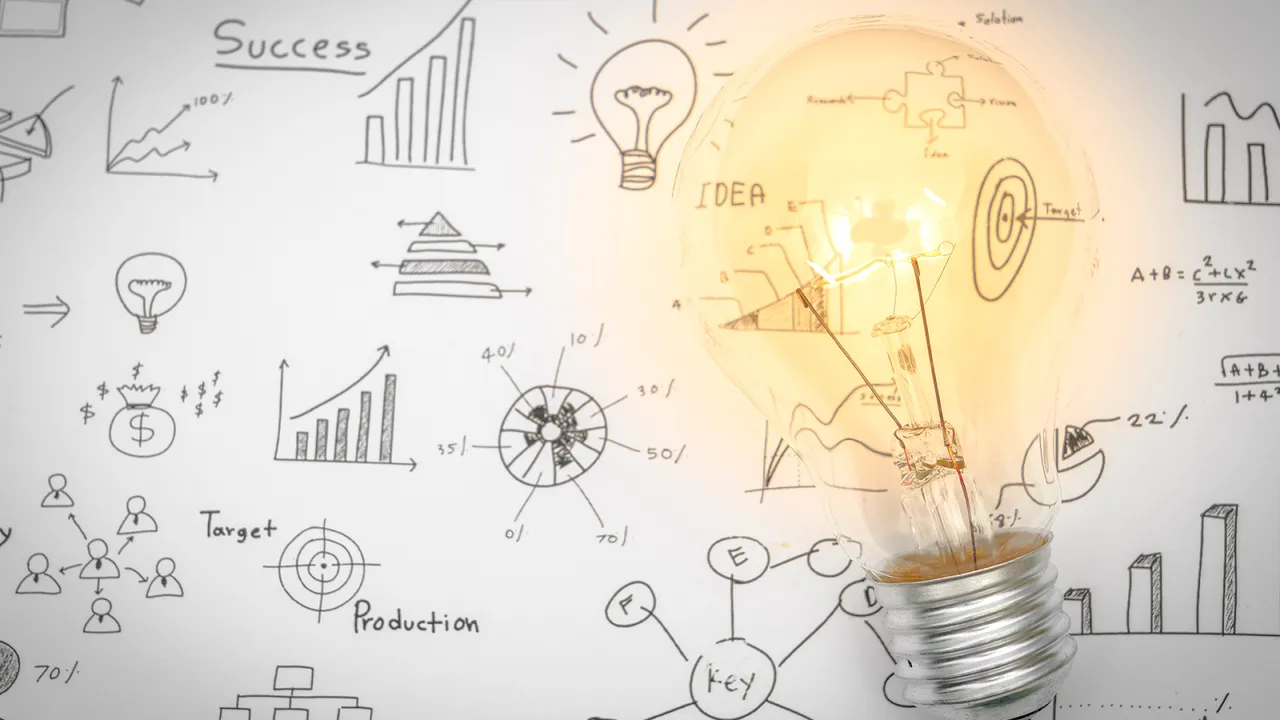 A glowing light bulb placed over a whiteboard filled with hand-drawn business charts, graphs, and ideas symbolizing strategic planning.