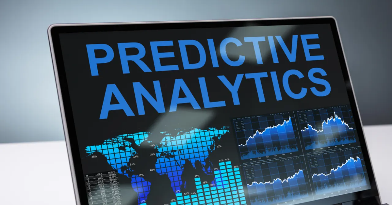 A computer screen displaying the words 'Predictive Analytics' alongside global data maps and trend charts, representing data-driven forecasting and decision-making.