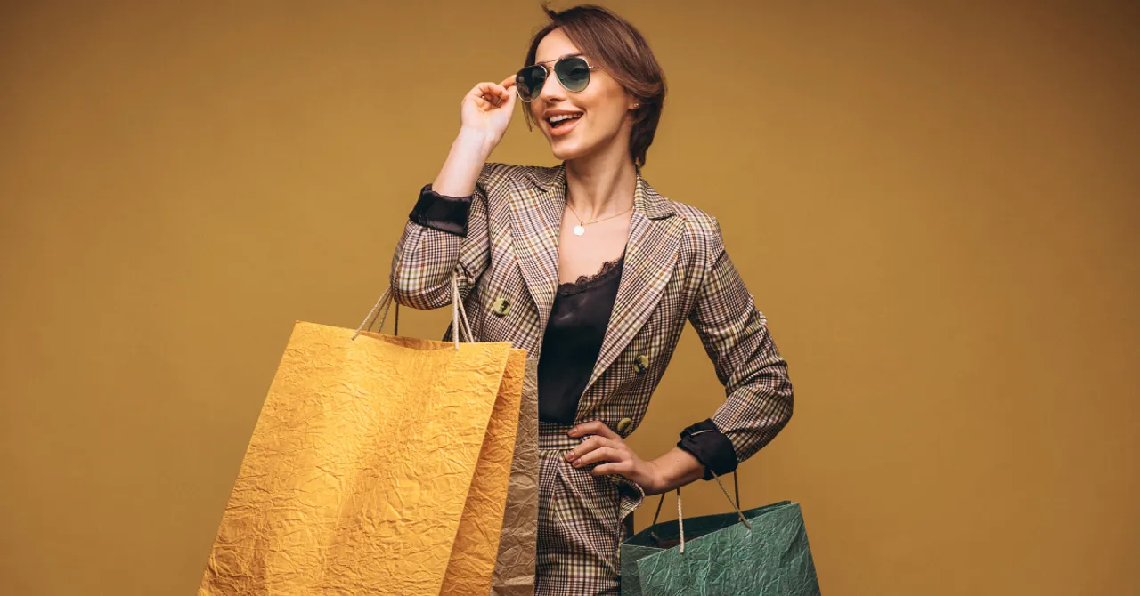A stylish woman smiling with shopping bags in hand — representing the confidence and satisfaction of finding the right products through a personalized shopping experience.