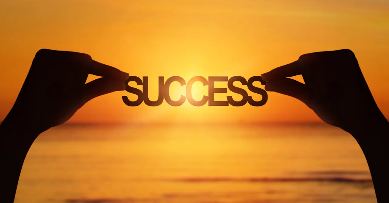 Hands holding the word “SUCCESS” against a glowing sunset — symbolizing achievement and the positive impact of guiding shoppers to the right choices.
