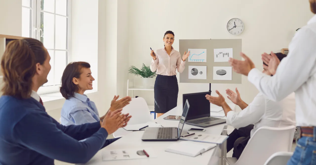 A woman leads a presentation while her team applauds — symbolizing how educating customers through skin quizzes builds trust and drives smarter buying decisions.