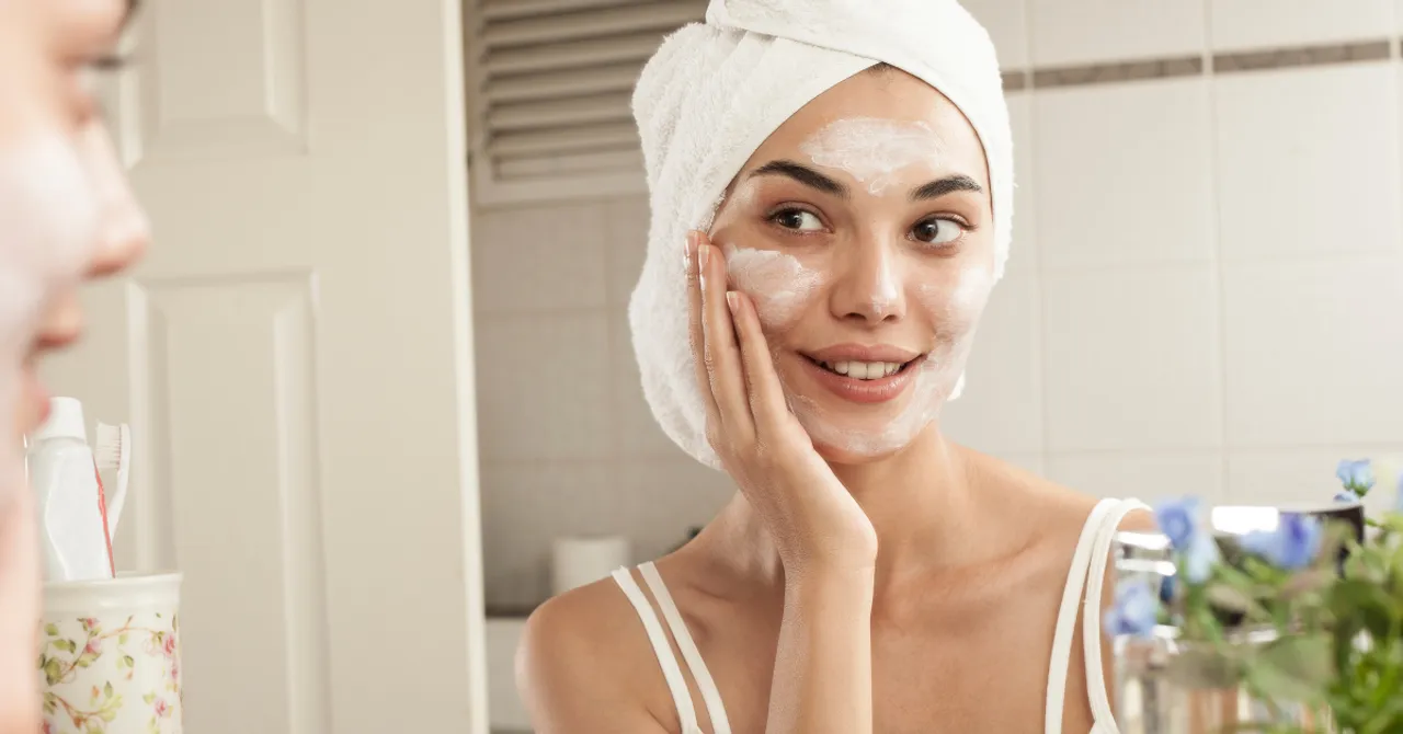A woman applies skincare while smiling in the mirror — representing how a Shopify app can help customers instantly find the right routine tailored to their skin needs.