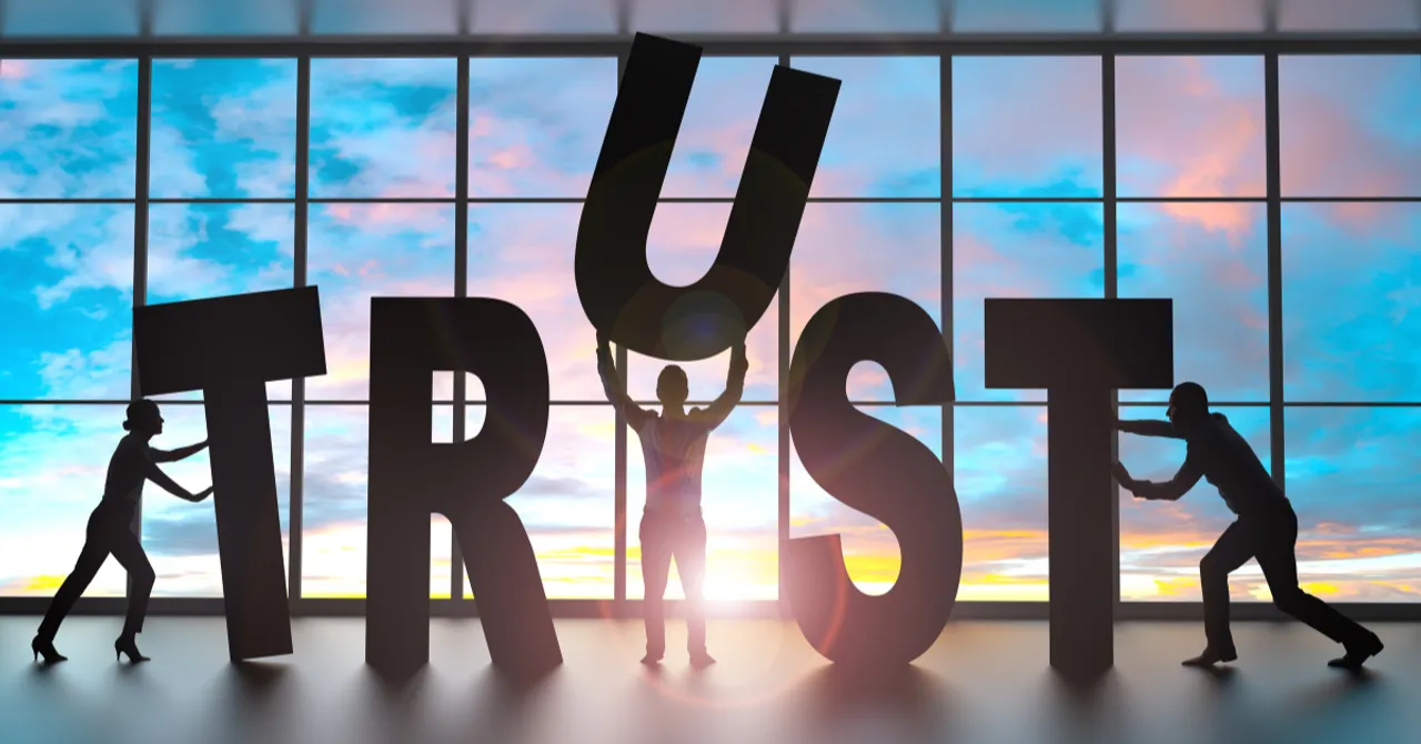 Silhouettes of people working together to build the word “TRUST,” representing how AI-powered recommendations can strengthen customer confidence through transparency and personalization.