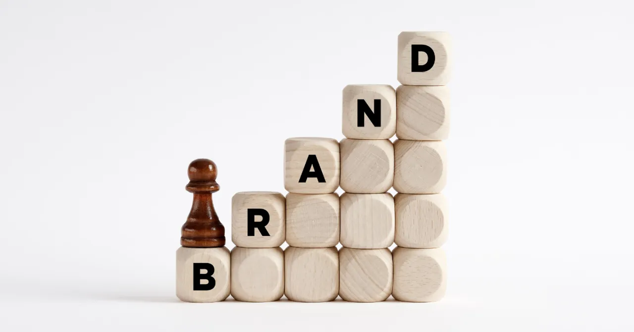 A wooden block staircase spelling out “BRAND” with a game piece climbing upward — symbolizing how clear, AI-driven product recommendations help build trust and elevate brand credibility.