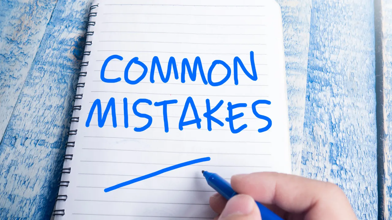 A hand writing "Common Mistakes" in blue ink on a notebook, highlighting typical errors merchants make when setting up upsell strategies after the 'Add to Cart' stage.