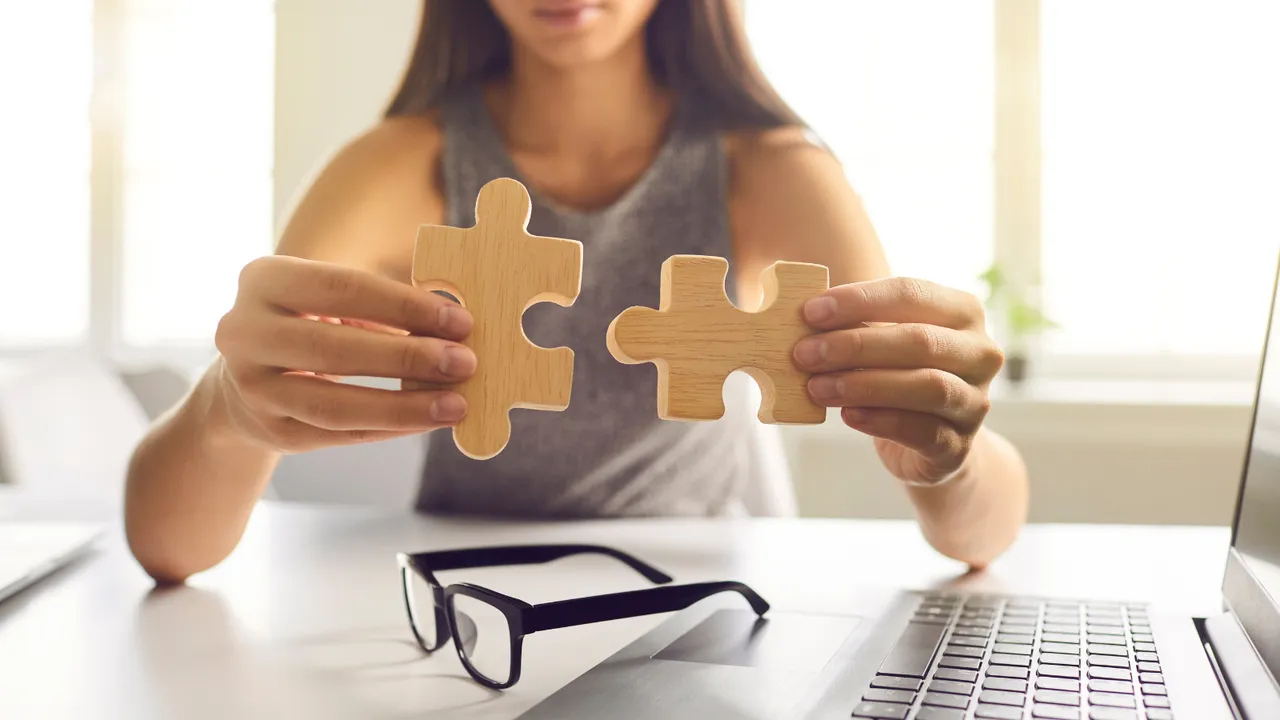A woman holding two wooden puzzle pieces about to connect, symbolizing how Supercart’s smart upsell solutions fit seamlessly into your existing e-commerce sales strategy to increase AOV.