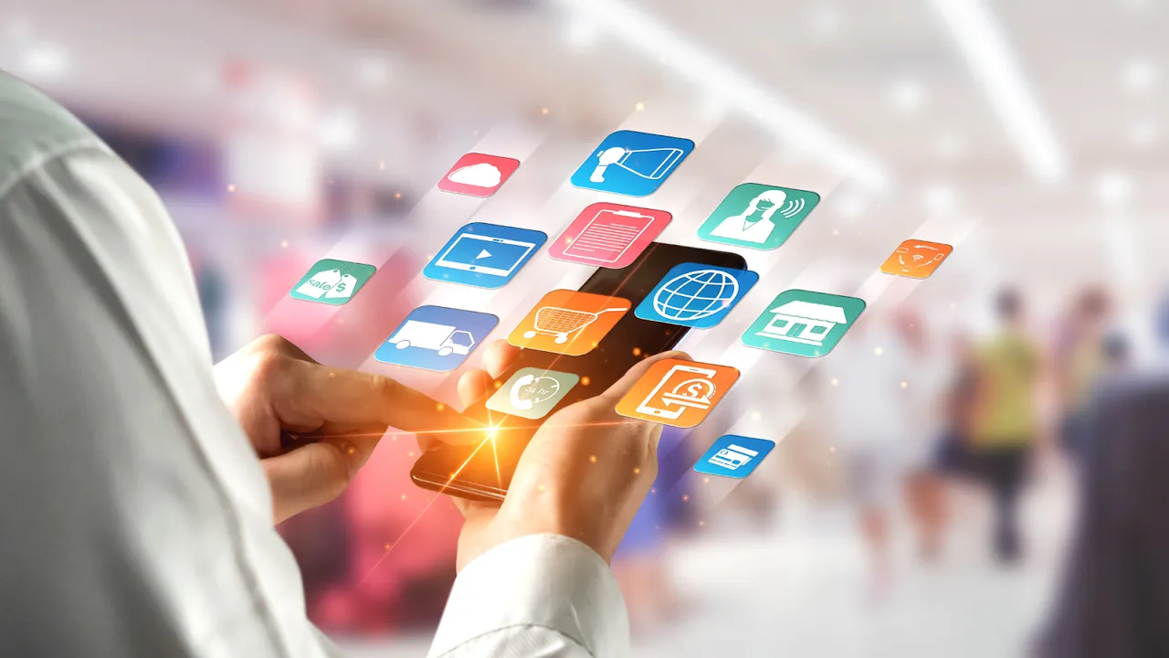 Person using a smartphone with floating eCommerce and marketing icons, symbolizing multichannel digital engagement and mobile shopping.