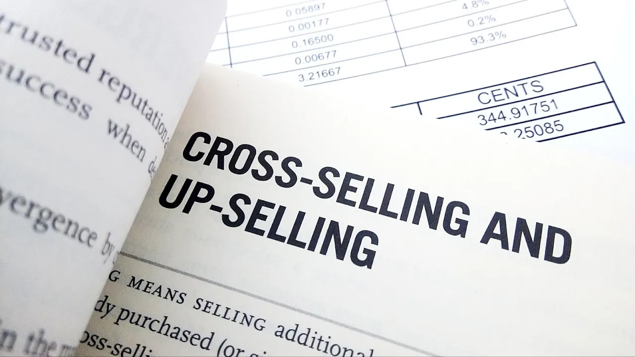 Close-up of a book page highlighting the terms "Cross-Selling and Up-Selling" with financial charts in the background, representing key strategies to increase sales and customer value in eCommerce and marketing.