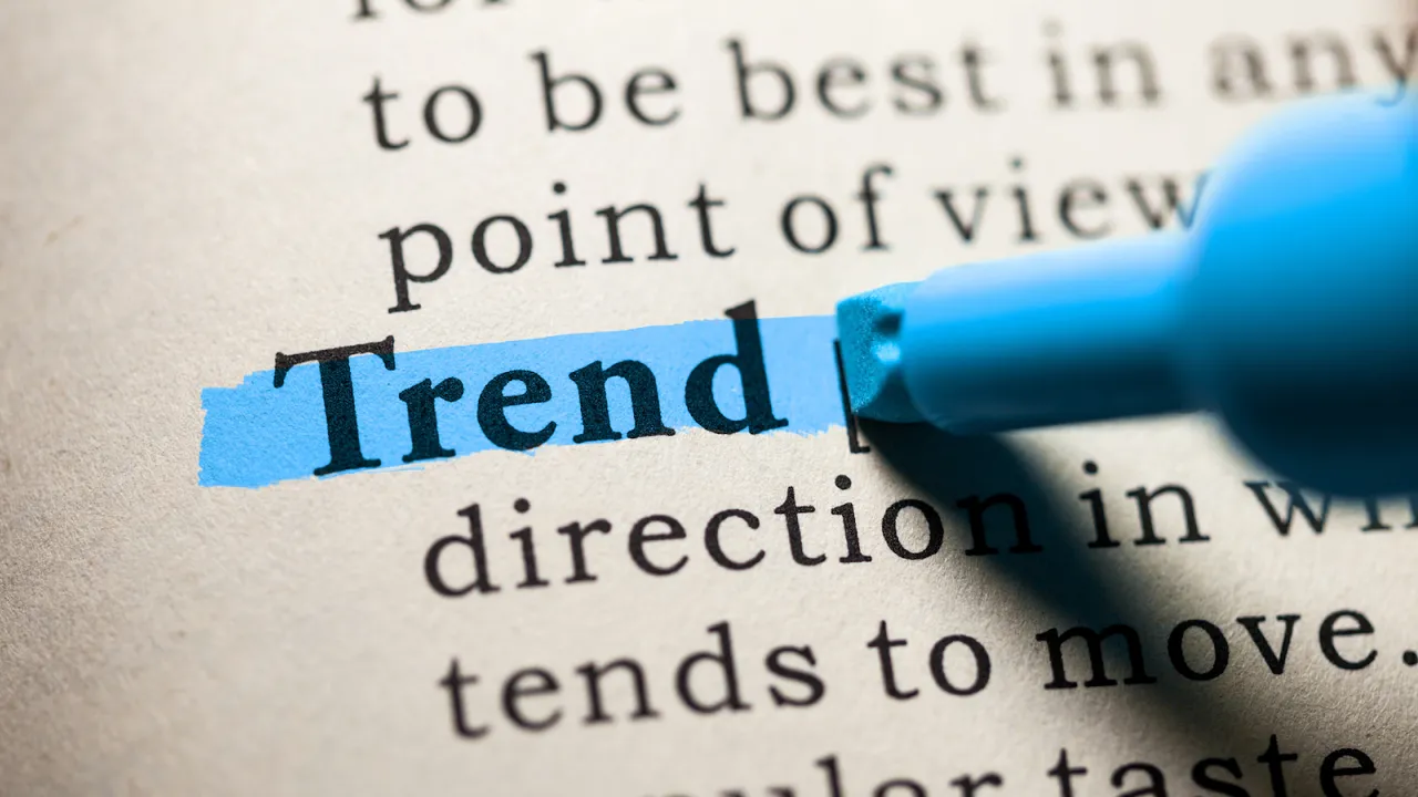 Close-up of the word "Trend" being highlighted in blue in a dictionary, symbolizing emerging topics or popular directions in business and marketing.